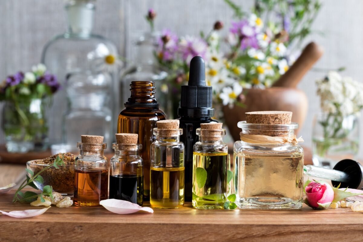 Small Amber Glass Bottles Surrounded by Colorful Wildflowers on a Rustic Wooden Table