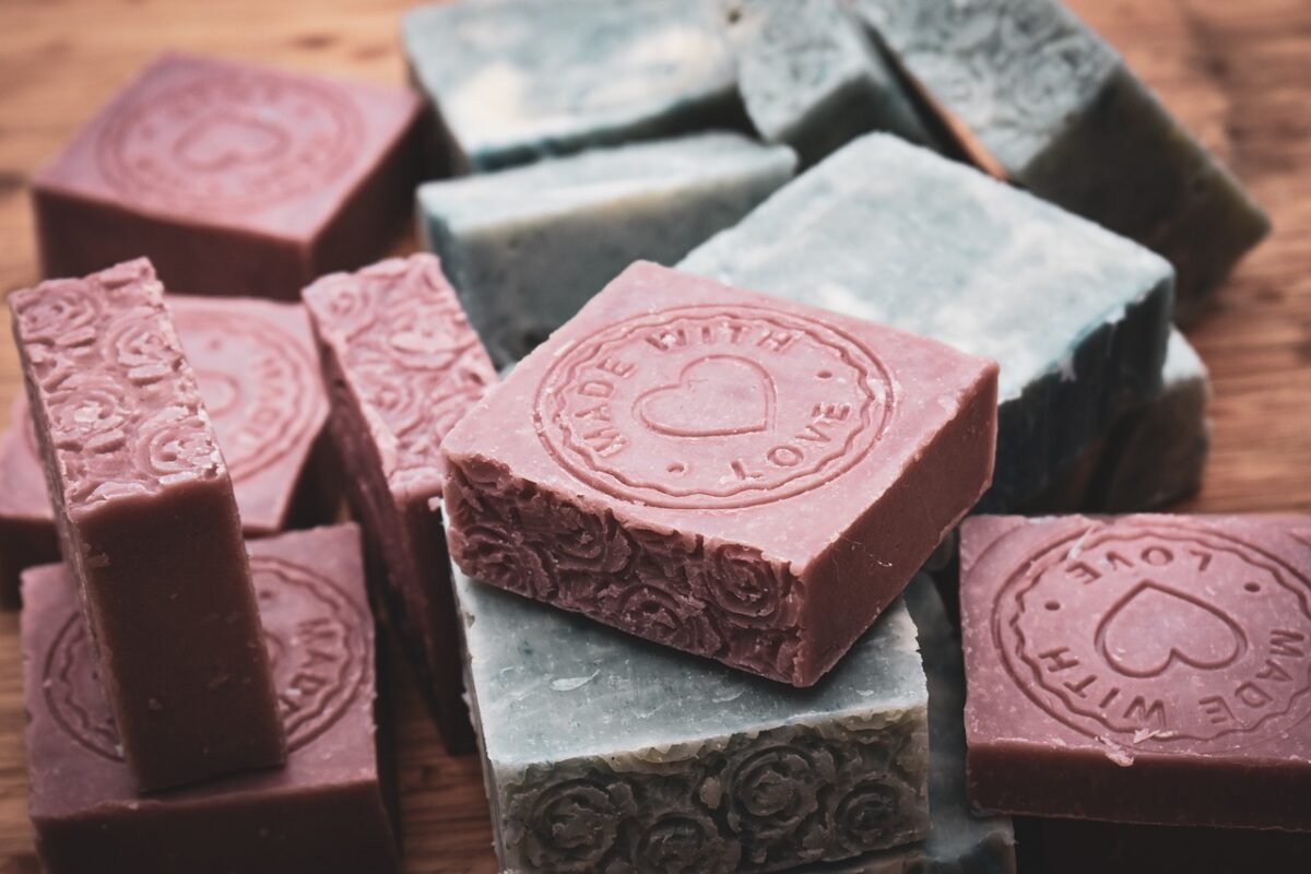 Artisan Soap Collection. Various Bars of Soap in Pink and Gray, with Pink Bars Featuring 'Made with Love' Circular Stamps and Decorative Floral Patterns, Highlighting the Artisanal Craftsmanship